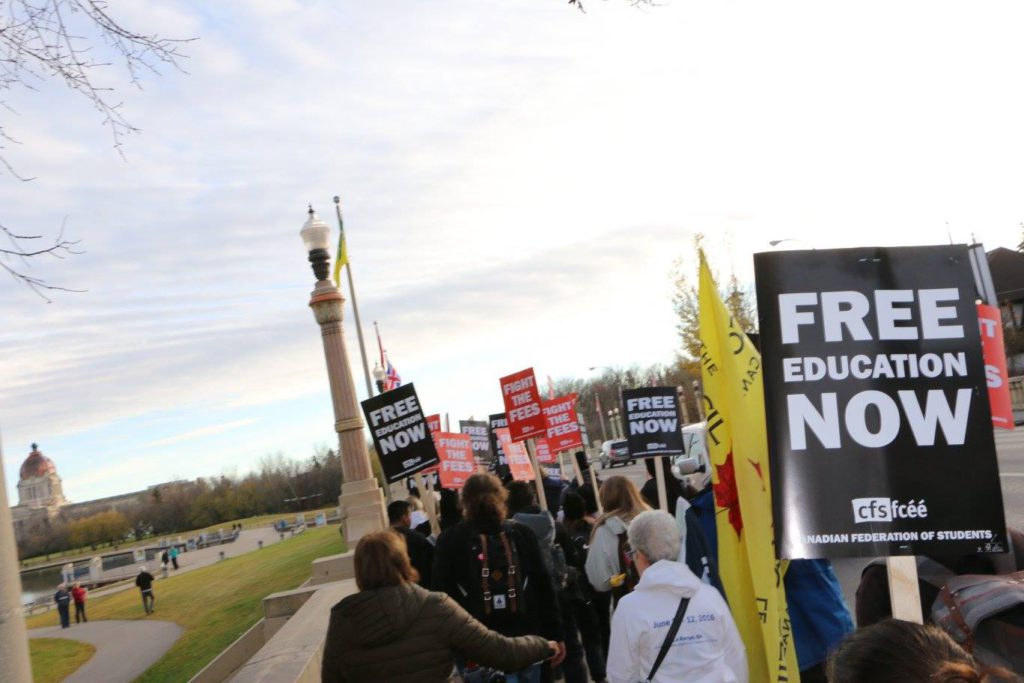 Members of URSU, FNUniv SA, and the CFS march south on Albert Street Bridge near Wascana Lake with the Legislative Assembly of Saskatchewan in the distance. They march with members of the public and other community groups to demand a freeze on tuition increase and the rising cost of education on November 3, 2016.